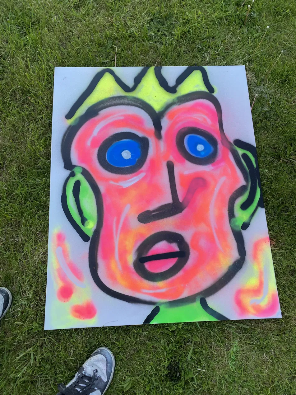 Bright spray paint portrait of a face with blue eyes, neon pink and orange skin and a yellow crown
