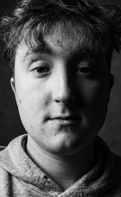 Black and white portrait photograph of Alex looking calmly at the camera